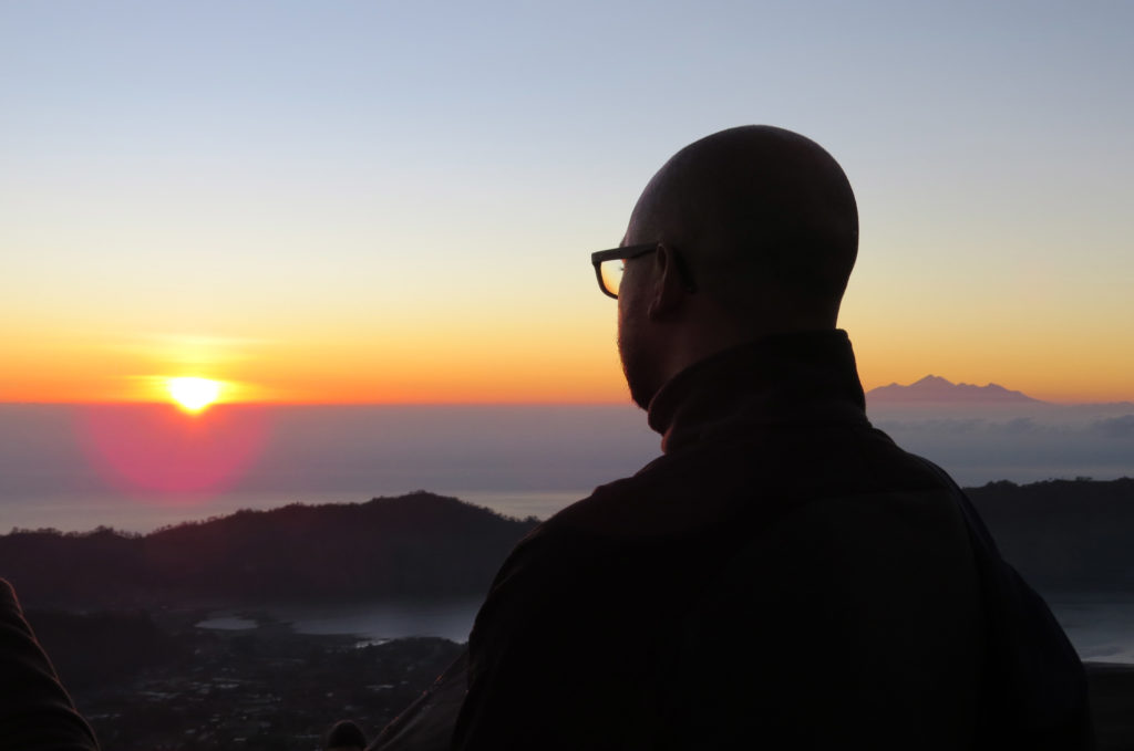 quel voyageur de dos regarde soleil levant sur mont Batur Bali Indonésie