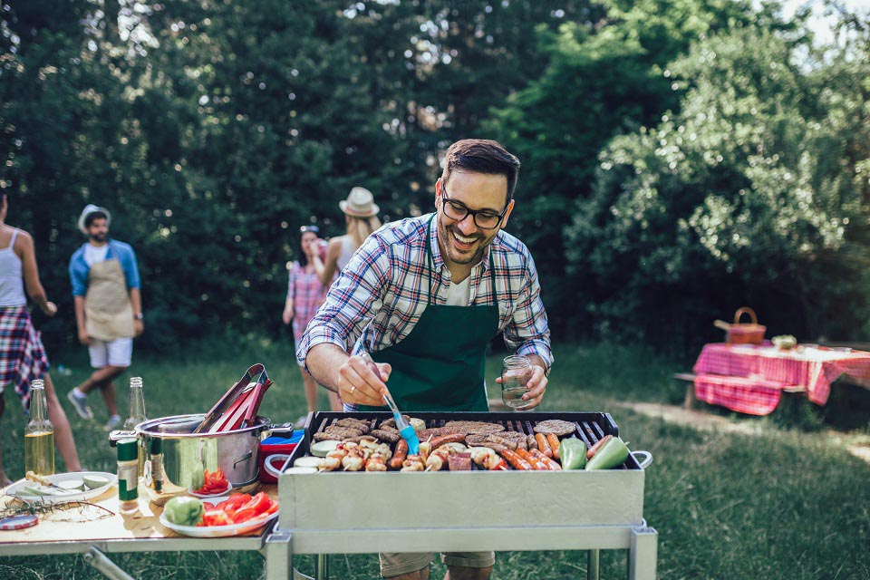 Handsome male preparing barbecue outdoors for friends Homme qui prépare le barbecue lors d'un séjour Crossfit